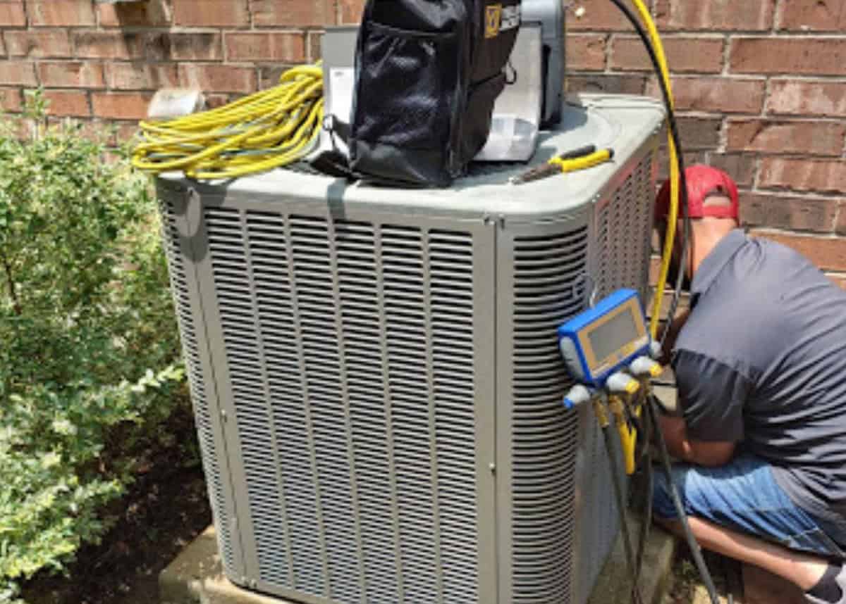 HVAC technician performing a tune-up on an AC unit in the Dallas area.